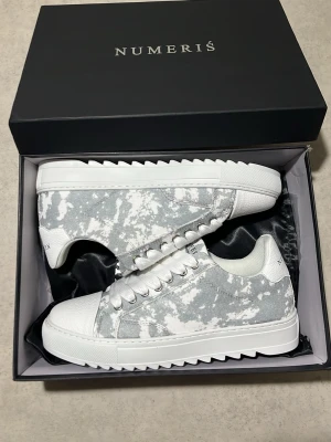Numeris - Säljer ett par snygga Numeris sneakers i vitt/grått mönster. Riktigt clean design som passar till allt. Skorna är i storlek 41 men eftersom skorna stora i storlek så passar dem även i storlek 42 