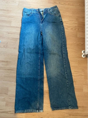 Blåa raka/ baggy jeans - Säljer ett par blåa jeans med rak / baggy passform och rå, fransig kant nertill. Jeansen har klassisk femficksdesign och är tillverkade i denim. Perfekta för en avslappnad och trendig look.