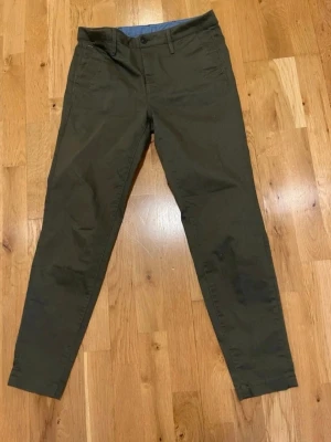 Mörkgröna chinos från G star raw stl 36 - Snygga mörkgröna chinos från G star raw med raka ben och klassisk passform. Byxorna har två sidofickor, bälteshällor och en diskret logga vid fickan. Tillverkade i mjukt bomullstyg med en skön känsla och blått innerfoder i midjan.