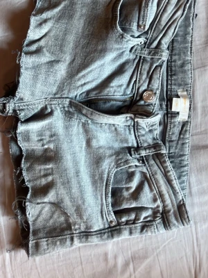 Grå jeansshorts med rå kant - Snygga grå jeansshorts med rå, fransig kant och klassisk femficksdesign. Jag har klippt ett par jeans från Gina i storlek 152