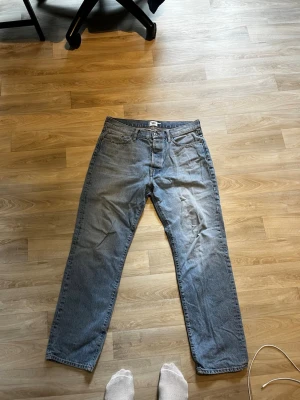Ljusblå raka jeans 157, W32 L32 - Säljer ett par ljusblå jeans från 157 med rak passform. Klassisk femficksmodell och gylf med dragkedja. Jeansen är i bomull och har en avslappnad look som passar till det mesta. Perfekta för dig som gillar en enkel och stilren stil.