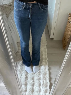 Blå bootcut jeans från Levi's - Snygga blå bootcut jeans från Levi's med klassisk femficksdesign och normal midja. Jeansen har en lätt utsvängd passform nertill och är tillverkade i denim med en liten stretch för extra komfort. Perfekta för en trendig och avslappnad look.
