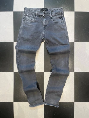 Grå slim fit jeans från Replay - Snygga grå slim fit jeans från Replay med klassisk femficksdesign och diskreta slitningar. Jeansen har en modern passform och är tillverkade i stretchigt denim för extra komfort. Perfekta för en trendig och avslappnad stil.