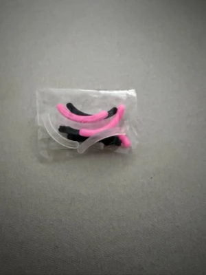 Tillbehör till ögonfransböjaren - Ett set med böjda silikonpads i rosa och svart, perfekta för ögonfranslyft eller permanent. Padsen är små, flexibla och kommer i en genomskinlig plastpåse.