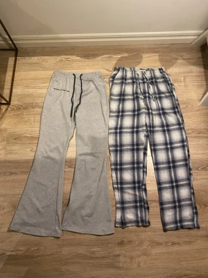 Tre par mjukisbyxor, grå, rutiga och svarta med vita ränder.  - Säljer tre par pyjamasbyxor – ett par grå med utsvängda ben och dragsko i midjan, ett par blåvitrutiga med rak passform och resår i midjan, samt ett par svarta med tre vita ränder från addidas. Perfekta för mysiga hemmakvällar.