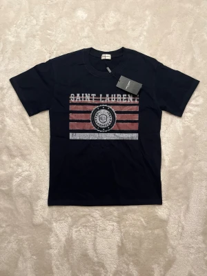 Saint Laurent T-Shirt S - Tja! Säljer nu denna riktigt feta Saint Laurent t shirten. Perfekt nu till sommaren! Storlek S. 