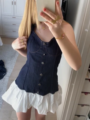 Sommar klänning - Supersöt kort jeansklänning med halterneck och knappar framtill. Överdelen är i mörkblå denim med markerade sömmar och kjolen har en vit volang. 💕ganska stretchigt material så passar både XS och S💕