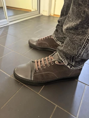 Mörkgrå Lanvins - Snygga mörkgrå Lanvins, kombinerat mocka och lädermaterial. Skorna har matchande grå snören och svarta sulor. Perfekta för dig som gillar en stilren och clean look till vardagsoutfiten. Det finns lite slitage längst fram på skorna. Det som tillkommer är orginalförpackning och påsar till skorna från Lanvin. Kvitto finns om så önskas. Inköpta på NK.