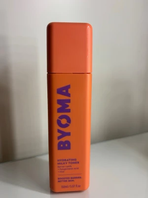 BYOMA Hydrating Milky Toner - En återfuktande milky toner från BYOMA i en snygg orange plastflaska med lila text. Innehåller barrier lipids, polyglutamic acid och cica för att stärka hudbarriären och ge bättre hud. Flaskan rymmer 150 ml och har en modern, fyrkantig design. Vet inte hur mycket det är kvar men mer än halva iallafall!