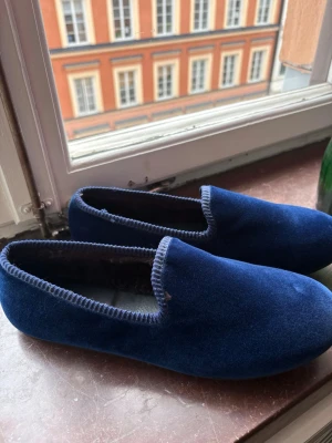Blå sammetsstofflor från Hums. - Mörkblå tofflor i mjuk sammet från Hums. Klassisk slip-in modell med låg kant och diskret söm runt öppningen. Insidan är fodrad med mjukt material för extra komfort. Den perfekta inneskon. Endast använda tre gånger inomhus.