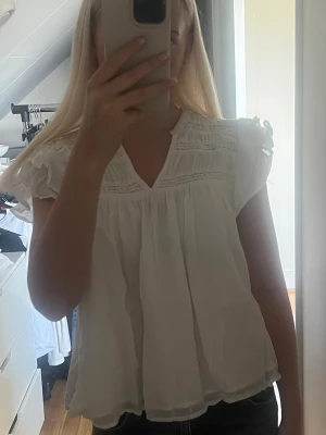 Vit topp/blus - Supergullig vit blus med v-ringning och volangärmar från gina tricot. Fina spetsdetaljer upptill och ett lätt material som faller perfekt!