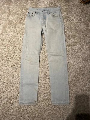 Ljusblå raka Levi's jeans - Säljer ett par ljusblå Levi's jeans med klassisk femficksdesign och raka ben. Jeansen har en vintagekänsla och är tillverkade i 100% bomull. Perfekta för en avslappnad och trendig look. Skulle säga att storleken är L28 W28.