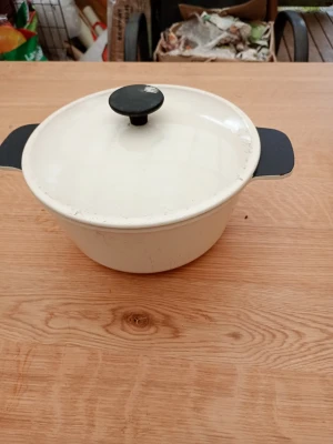 Vit emaljerad gryta med lock - Säljer en rund vit gryta i emalj med svart lockknopp och svarta handtag. Perfekt för långkok och grytor. Grytan har en klassisk design och passar bra i köket för matlagning till flera personer. 2-3 liters . Sparsamt använd.