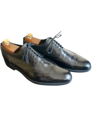 Svarta loafers från Loake 1880 - Stilrena svarta loafers från Loake 1880 i blankt läder med klassisk broguemönstring och rundad tå. Skorna har gummisula med bra grepp och levereras med originalkartong och skoputs från Saphir. Perfekta för dig som gillar tidlös och elegant stil. I mycket fint begagnat skick. 