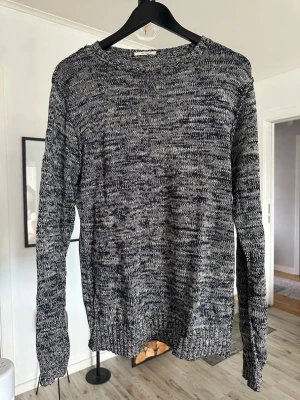 Melerad stickad tröja från GANT - Säljer en snygg melerad stickad tröja från GANT Rugger i mörkblått och vitt. Tröjan har rund halsringning, långa ärmar och ribbade muddar. Perfekt för dig som gillar en avslappnad men stilren look.