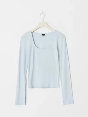 Ljusblå långärmad topp  - Säljer en ljusblå långärmad topp från Gina Tricot med rundad, djup ringning. Toppen är figurnära och har en enkel, stilren design som passar perfekt till jeans eller kjol. Tillverkad i mjuk bomullsmix för en bekväm känsla.