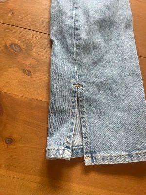 Ljusblå jeans med slits från 157 - Säljer ett par ljusblå jeans från 157 i storlek XS. Jeansen har en rak passform och en snygg slits vid benslutet som ger en trendig look. Tillverkade i klassisk denim med synliga sömmar. Perfekta för dig som gillar en avslappnad men stilren stil. Hör av er om ni har frågor 🥰