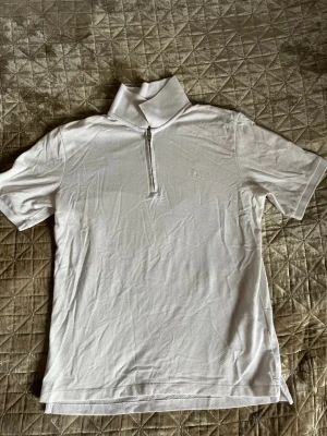 Vit polotopp med half zip - Vit polotopp med kort ärm och half zip framtill. 