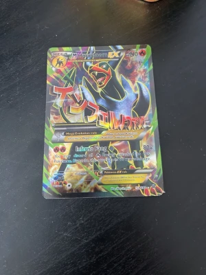 Pokémonkort Mega Houndoom EX - Säljer ett samlarkort från Pokémon, Mega Houndoom EX. Kortet har färgstark och glansig design med japansk text och motiv av Houndoom. Perfekt för dig som gillar Pokémon eller samlar på trading cards.