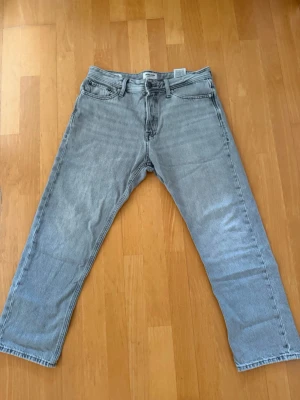 Jack & Jones Jeans - Säljer ett par ljusgrå jeans från Jack & Jones, i klassiska loose Chris. Jeansen har en snygg tvättad look och är tillverkade i denim av bomull. Perfekta för en avslappnad och trendig stil. Passar dig som är cirka 180cm lång. Tveka inte om du har en fråga! Skick 8,5/10.