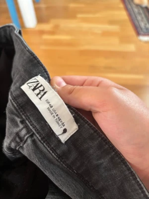 Svarta bootcut jeans från Zara - Säljer ett par svarta bootcut jeans från Zara med klassisk femficksdesign och normal midja. Jeansen har en lätt tvättad look och är tillverkade i ett mjukt denimtyg som sitter skönt. Perfekta för dig som gillar en avslappnad men trendig stil.
