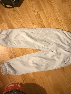 Ljusa mjukisbyxor från Reebok - Säljer ett par ljusgrå mjukisbyxor från Reebok med resår i midjan och vid bensluten. Klassisk avslappnad passform och diskret logga på benet. Perfekta för chill dagar eller träning.