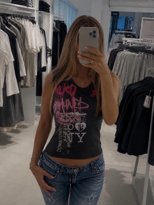 Y2k vintage tröja ifrån Tommy hilfiger  - Snygg ärmlös topp från Tommy Hilfiger med graffitiinspirerat tryck i rosa, vitt och silver på framsidan. Toppen har rund halsringning och fin passform. ❗️Väldigt eftertraktad och går inte att köpa längre. ❗️(Kan vara klippta ärmar, som syns på bilderna, osäker då den är så gammal) Perfekt för dig som letar vintage kläder från riktiga märken! 