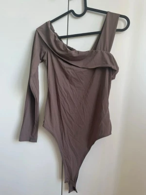 Body  - Snygg brun off shoulder-body med asymmetrisk design. Mycket sparsamt använd 