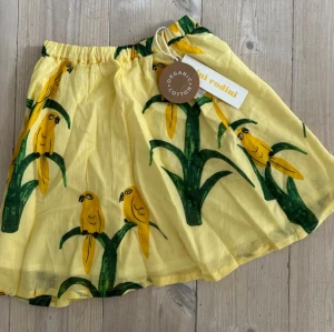 Ny! Gul kjol med livfullt mönster från Mini Rodini, stl 80/86 - En ljuvlig gul kjol med ett livfullt mönster av gula papegojor från Mini Rodini, stl 80/86. Ny med prislappen kvar! Rökfritt hem.