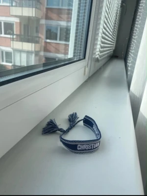 Blått armband - Snyggt blått tygarmband  med vita detaljer'. Armbandet har justerbara tofsar i ändarna och en cool, bohemisk vibe. Perfekt accessoar för att lyfta din outfit. Pris kan diskuteras minst 130