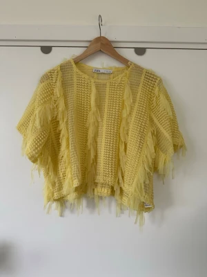 Gul meshtröja med fransar från ZARA - storlek S - Unik gul tröja från ZARA med korta ärmar, meshdetaljer och fransar över hela plagget. Oversized passform och luftig design som ger en cool och trendig look. Perfekt för dig som vill sticka ut och älskar statement-plagg. Storlek S, men passar M också, men då med mer figurnära passform. Mycket gott skick, som ny!