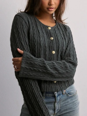 Mörkgrå kabelstickad kofta - Snygg mörkgrå kabelstickad kofta med rund hals och  guldfärgade knappar framtill. Koftan har långa ärmar och en croppad passform. Materialet är mjukt och mysigt. 