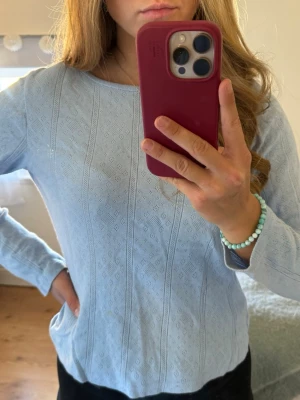 Ljusblå stickad tröja med diskret mönster - Säljer en ljusblå stickad tröja med lång ärm och rund halsringning. Tröjan har ett diskret, invävt mönster i tyget som ger en stilren look. Perfekt för dig som gillar mjuka pasteller och enkel design.