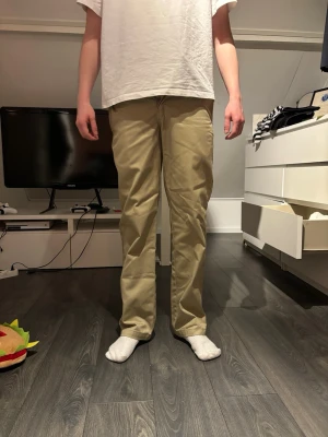 Beiga chinos med rak passform - Snygga beiga chinos med rak passform och klassisk design. Byxorna har normal midja och diskreta sidofickor. Tillverkade i ett mjukt och bekvämt bomullsmaterial som passar perfekt till en avslappnad stil. Inga synliga loggor eller märken.