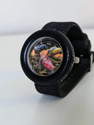 Klocka Barnklocka Cars Disney Pixar - - Oanvänd har bara förvarats i en låda så den är i jättefint skick.  - Nytt batteri behövs då den är urladdad.  - Jag garanterar ej och ansvarar ej för om den funkar eller ej vid batteribyte men den bör göra det då den inte har använts   - Tror den köptes på ur och penn det var iaf en fysisk butik vi köpte den på.  Obs: Jag kan ha missat någon miniskavank men jag har försökt att granska plagget så gott det går