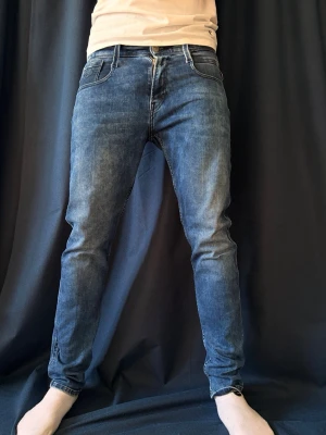 Blå slim fit jeans från Replay - Säljer ett par blå slim fit jeans från Replay med klassisk femficksdesign och dragkedja. Jeansen har en snygg tvättad look och smal passform som sitter tajt längs benen. Perfekta för en trendig och avslappnad stil. Hör av dig vid minsta funderingar!