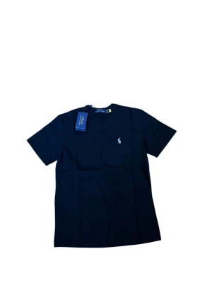 Marinblå t-shirt från Polo Ralph Lauren - Snygg marinblå t-shirt från Polo Ralph Lauren med klassisk rund hals och korta ärmar. T-shirten har den ikoniska broderade loggan i ljusblått på bröstet och är tillverkad i mjuk bomull för en skön känsla. Perfekt till jeans eller shorts.