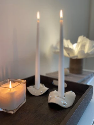 Handgjorda ljusstakar i lera - Två unika, handgjorda ljusstakar i beige med oregelbunden form och små vita kulor som dekoration. Perfekta för smala ljus och ger ett modernt, konstnärligt intryck till rummet. Säljes utan ljus.