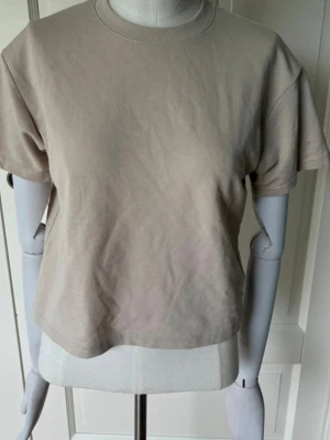 Beige t-shirt - En enkel beige t-shirt med lite croppad passform och rund hals. Tillverkad i mjuk bomull och har korta ärmar. Säljer pga att den inte används💓