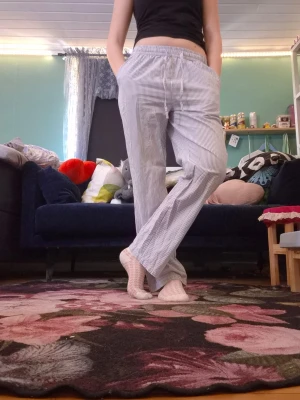 Randiga pyjamasbyxor med resårmidja - Säljer ett par klassiska pyjamasbyxor med tunna blå och vita ränder. Byxorna har rak passform, resår i midjan och sidofickor. Perfekta för att chilla hemma eller sova i. Materialet känns mjukt och luftigt.