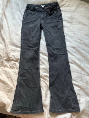 Svarta bootcut jeans med låg midja - Snygga svarta bootcut jeans med låg midja och klassiska fem fickor. Jeansen har utsvängda ben och är tillverkade i ett mjukt denimtyg som ger en avslappnad look. Justerbara i midjan! 