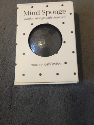 Mind Sponge konjacsvamp med kol - Konjacsvamp med aktivt kol från moshi moshi mind. Naturlig svamp som rengör och exfolierar huden skonsamt. Passar alla hudtyper och hjälper till att ge huden lyster. Svampen är svart och rund, tillverkad av konjacrot och kol.