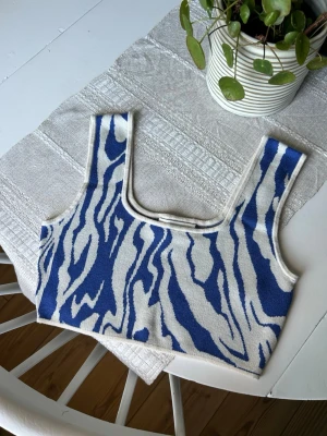 Blåvit stickad mönstrad topp - Säljer en stickad linnetopp med blått och vitt mönster från Monki. Toppen har breda axelband, fyrkantig uringning och croppad passform. 