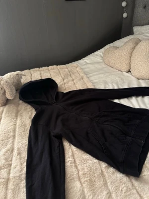 Svart hoodie med dragkedja - En klassisk svart hoodie med dragkedja framtill och huva. Hoodien har långa ärmar och två fickor på magen. Passar till det mesta i garderoben. Säljer för att jag hade 2 stycken.