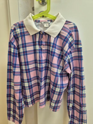 Rutig långärmad skjorta från Monki XS - Säljer en rutig skjorta från Monki i rosa, blått och vitt med klassisk vit krage och knappar framtill. Skjortan är tillverkad i 100% bomull och har långa ärmar. Perfekt för dig som gillar färgglada och bekväma plagg.