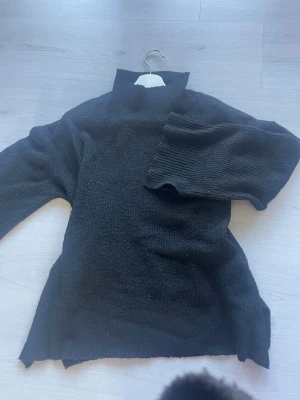 Svart polotröja stickad - Mysig svart stickad polotröja med breda ärmar och slitsar i sidorna och armarna. S/M