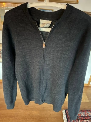 Svart stickad kofta från Bruun & Stengade - Klassisk svart stickad kofta från Bruun & Stengade med hel dragkedja framtill. Tröjan har rund halsringning och långa ärmar. Perfekt till lager på lager och enkel att matcha med olika outfits. Bra skick lite nopprig bara. Storlek M