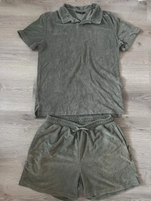 Grått loungewear-set från Reaction - Mysigt loungewear-set i grå frotté från Reaction. Setet består av en kortärmad pikétröja med krage och matchande shorts med dragsko i midjan. Perfekt för chill dagar hemma eller när du vill vara bekväm men ändå se snygg ut. Storlek S skick 9/10 knappt använd fåtal gånger men är som hely ny