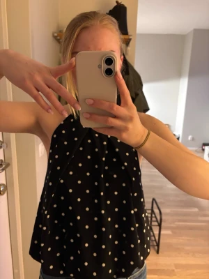 Svart prickig ärmlös topp - Säljer en svart ärmlös topp med vita prickar och öppen i ryggen från Hm. Helt oanvänd men prislappen kvar. Storlek xl men tycker mer att den sitter som en s/m om man vill ha en mer slapp passform. Referens brukar jag ha xs/s
