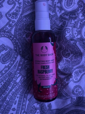 The Body Shop Fresh Raspberry Mist - Uppfriskande body mist från The Body Shop med doft av färska hallon. Kommer i en genomskinlig plastflaska med rosa etikett och spraymunstycke. Vegansk formula, passar normal till torr hud och ger en kylande känsla. Innehåller 100 ml.